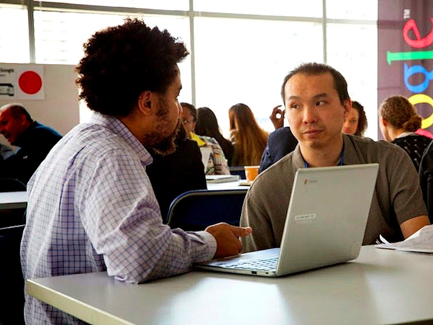 パソコンを挟んで話し合う男性2人