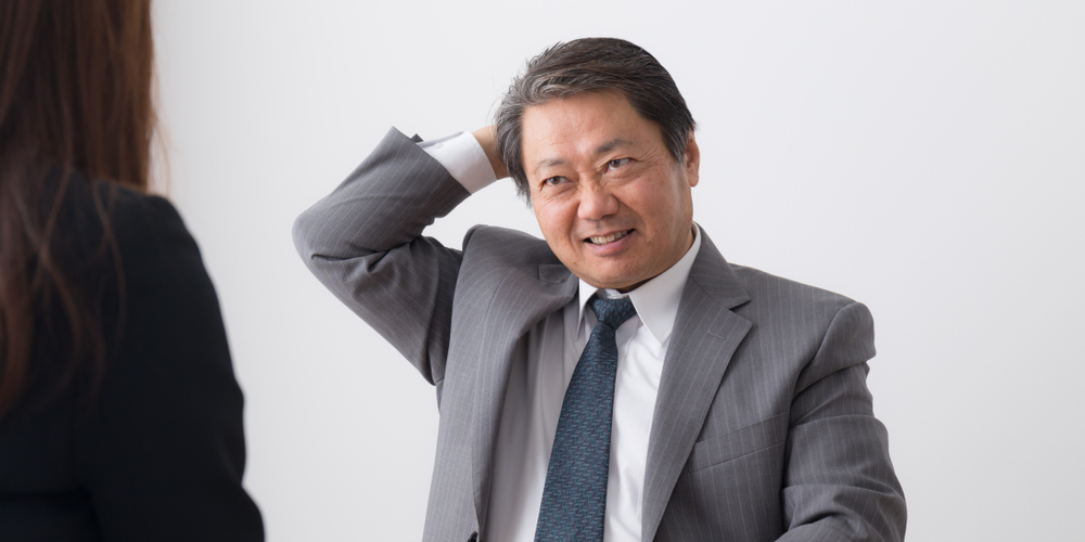 困った表情で頭をかく男性