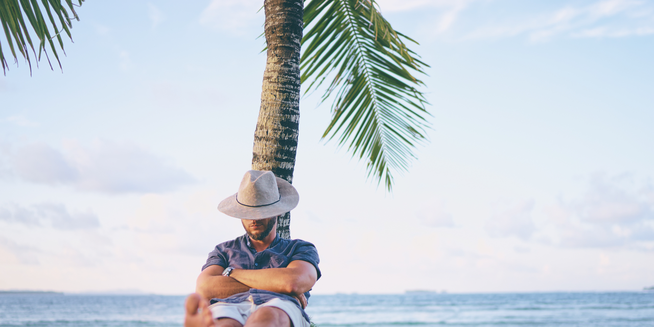 ヤシの木に寄りかかって眠る男性