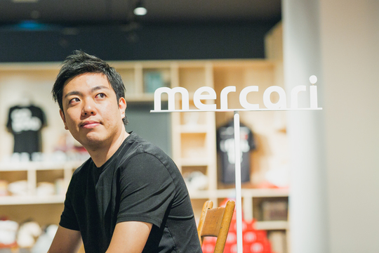 メルカリの唐澤さん。ロゴ前で