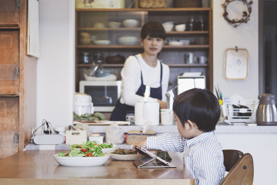 息子を見ながら食事を作る主婦