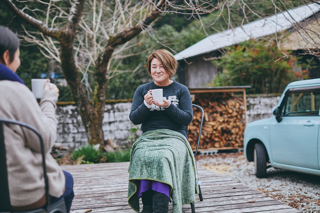 椅子に座ってコーヒーを持つ遠藤さん
