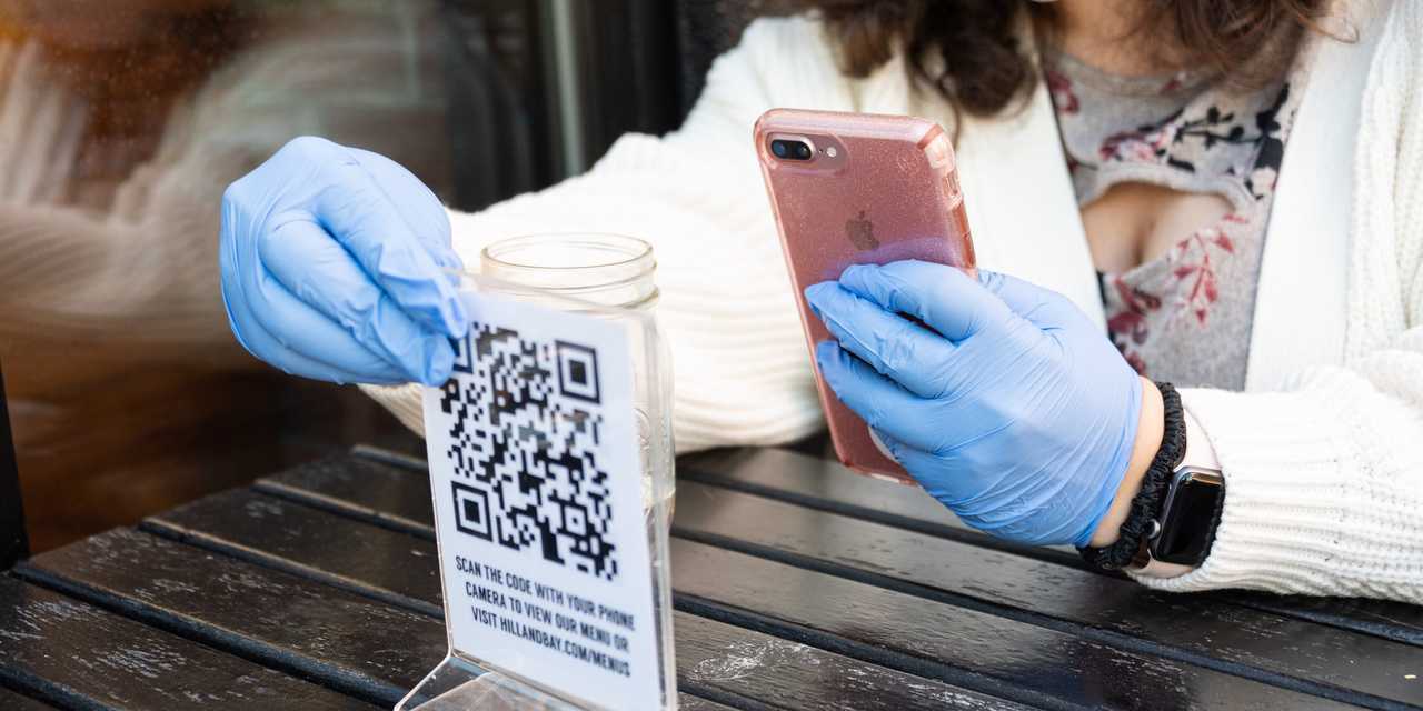  ニューヨークのレストランで、ゴム手袋をしてQRコードのメニューを読み取る客。