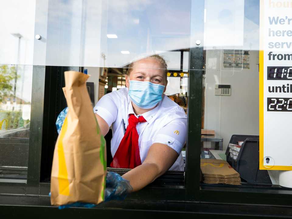 A McDonald's employee handing a customer their bag of food.