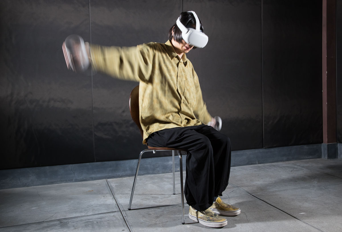 イスに座り、Oculus Quest 2で『POPULATION ONE』をプレイ