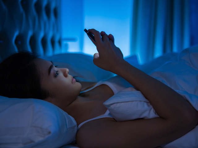ベッドでスマホを見る女性