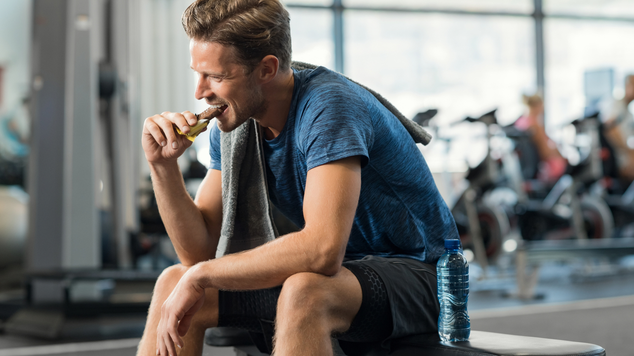 ジムでエネルギーバーを食べる男性