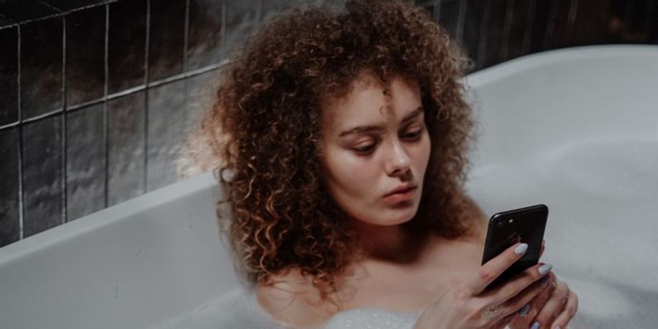 湯船の中でスマホを使う女性