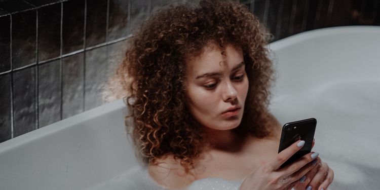 湯船の中でスマホを使う女性