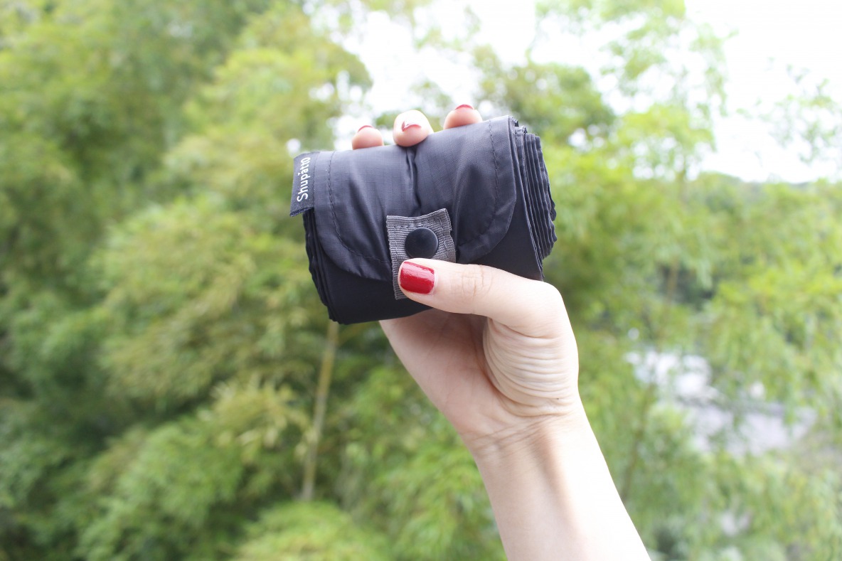 Shupatto「コンパクトバッグ（M）」をたたんで手に持つ