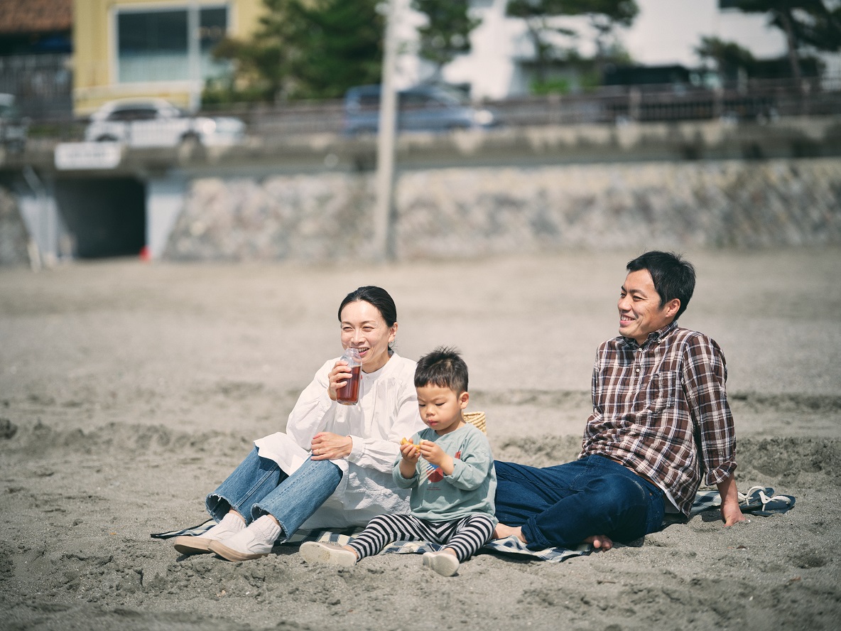 海辺に座って、柏木さんが麦茶を飲む