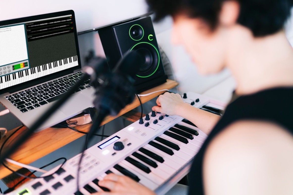 シンセサイザーで曲作りを行う男性