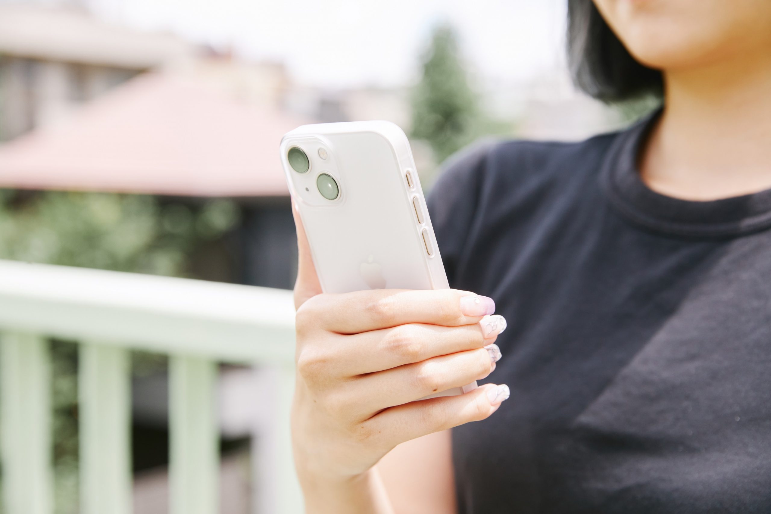 iPhone 13mini(スターライト)にTHE FROST AIR ULTRAのアイスホワイトを装着。女性がスマホを持つ