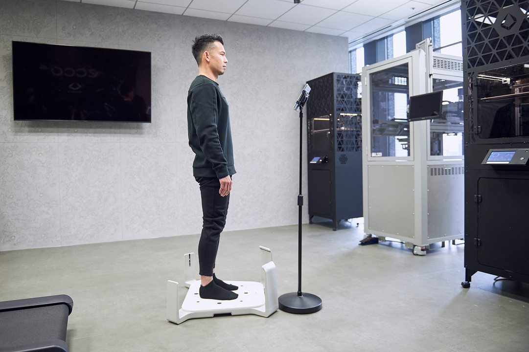 3D足型計測器に乗る菅原さん。わずか15秒で足を隅々までスキャンし、あらゆるデータを計測する。