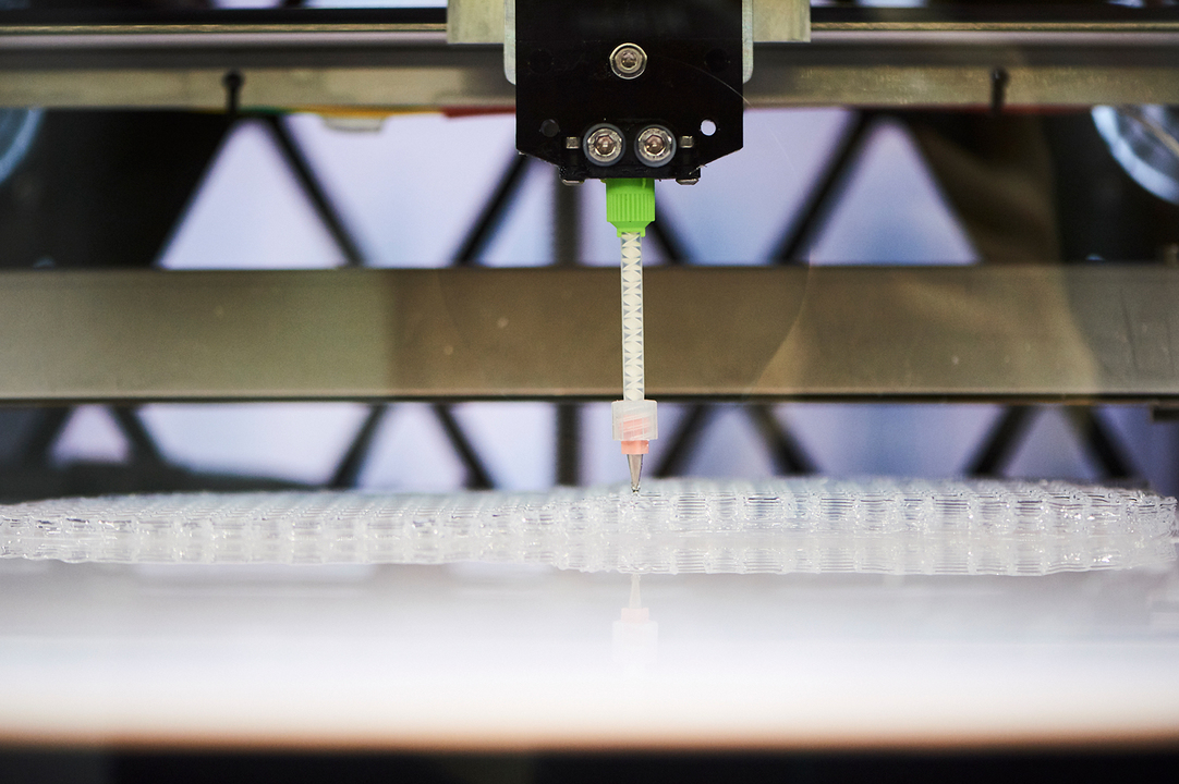 3Dプリンターの内部。ノズルから出るシリコーンの細い筋でミッドソールの層が形作られていく。
