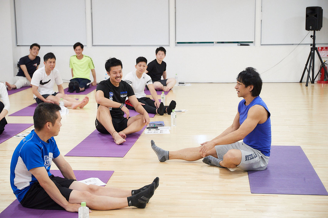 参加者とコミュニケーションを取りながら体前屈を実演する坂詰さん。