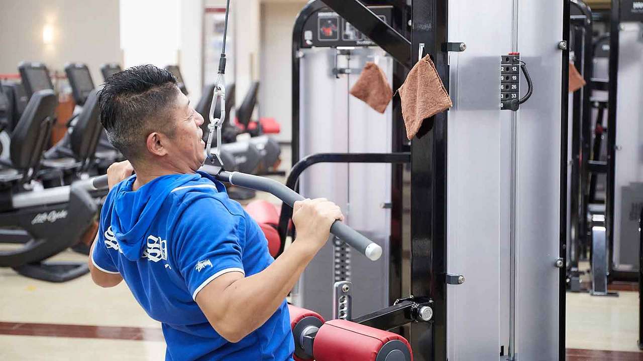 背中トレの主要マシン、ラットプルダウンで正しいフォームを実践する白戸拓也トレーナー