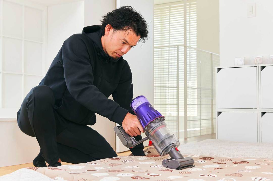 布団に掃除機をかけているトレーナー・菅原順二さん